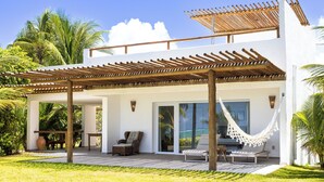 A modern villa with a covered patio, outdoor seating, and a hammock. - Aldeia Beijupirá Pousada (Porto de Pedras)