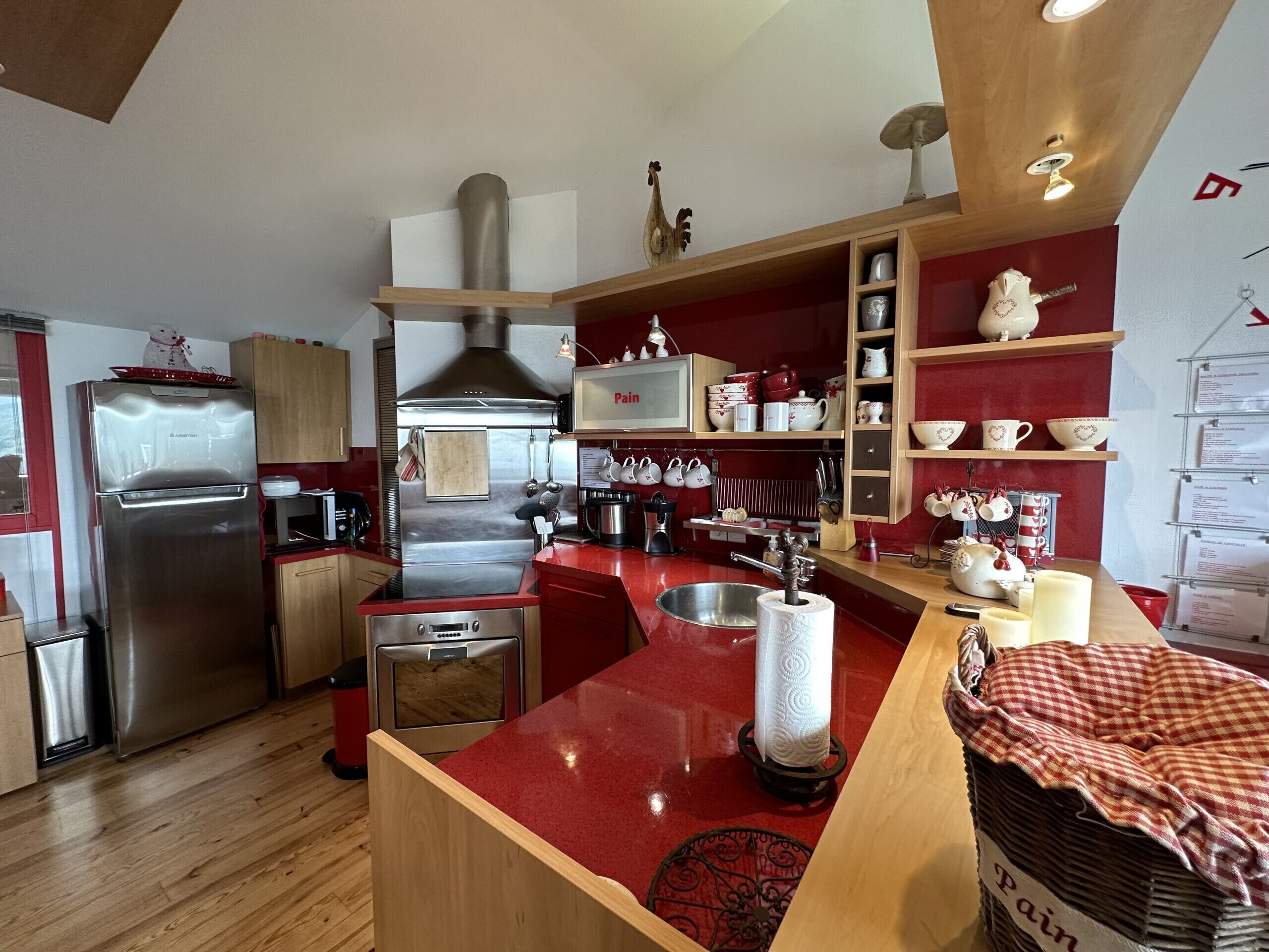 Une cuisine moderne dotée d’appareils électroménagers en acier inoxydable, de meubles en bois et d’un plan de travail rouge.