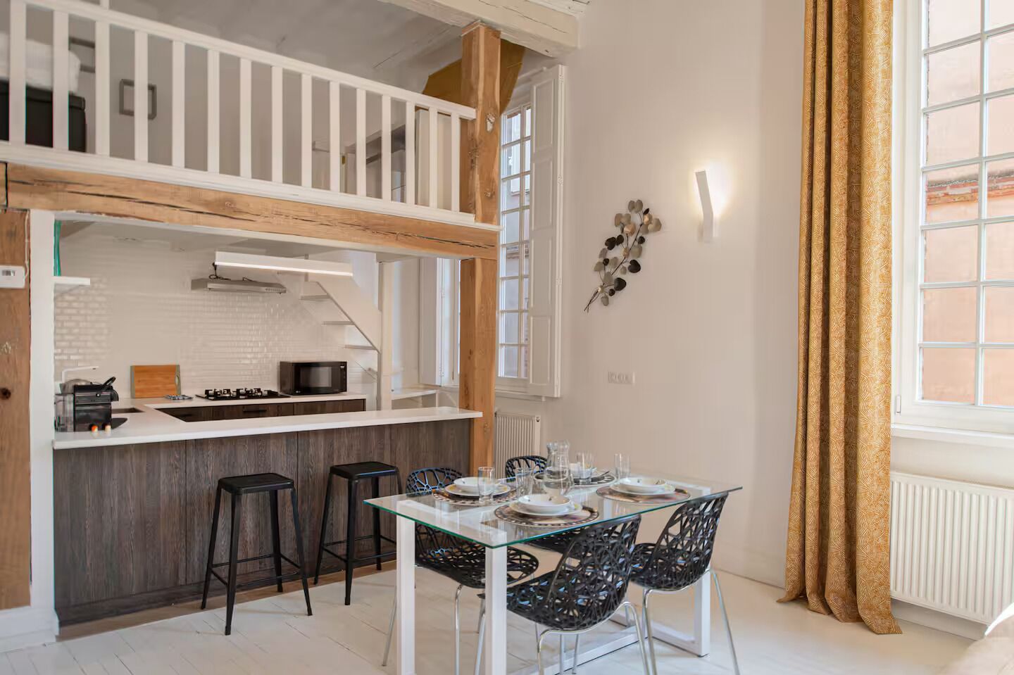 A modern kitchen with white cabinets, a wooden countertop, and a dining area with a glass table and black chairs.