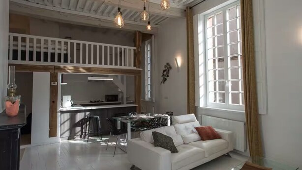 Un salon moderne avec un canapé blanc, une table basse en verre et un coin repas comprenant une table et des chaises blanches.