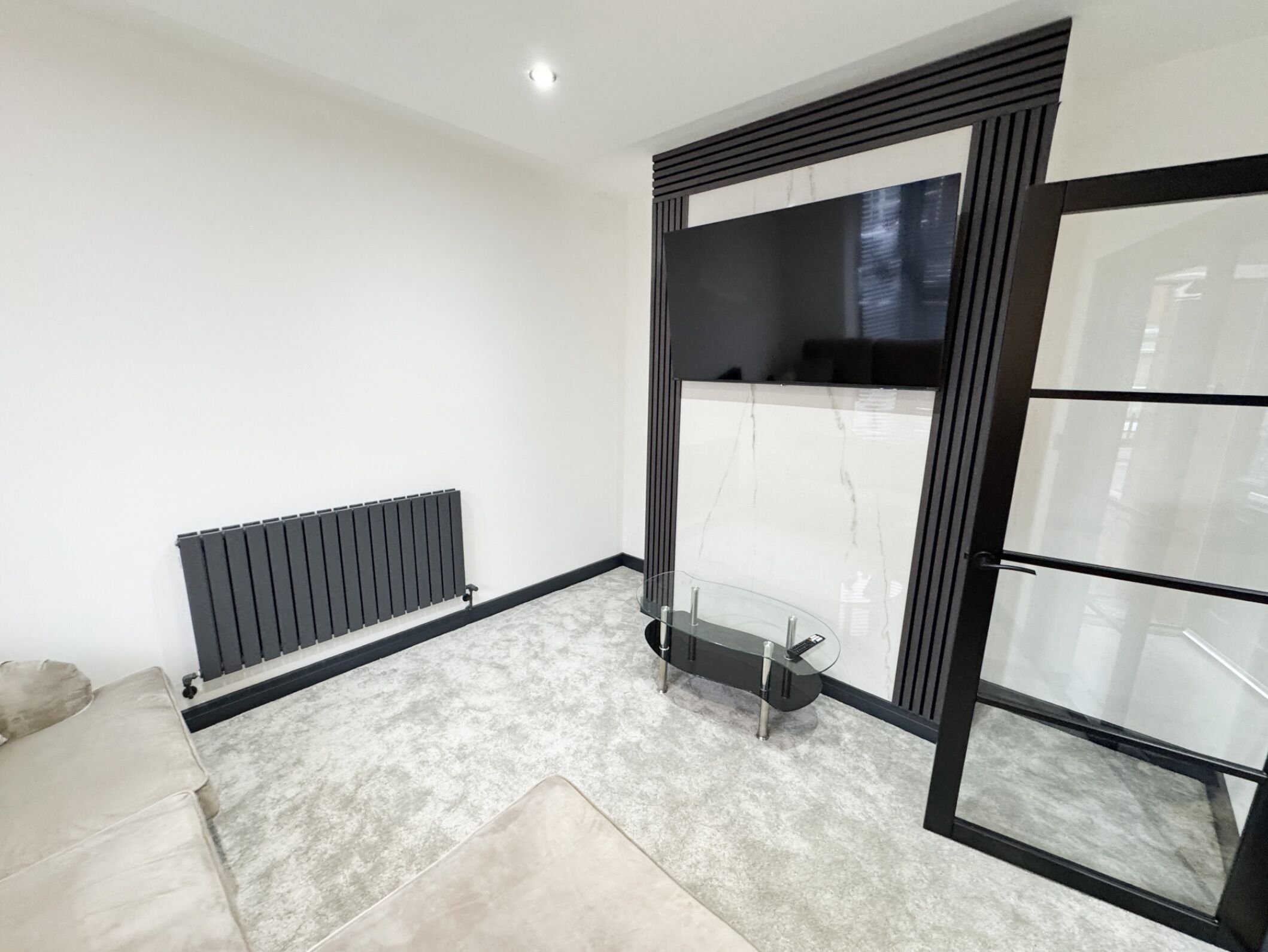 Un salón moderno con una mesa de centro de vidrio, un radiador y un sofá.