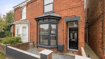 Stunning LOKINGTON HOUSE features a traditional facade with a black door and bay window.