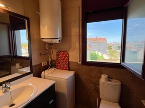 A bathroom with a sink, toilet, and a window with a view of buildings.