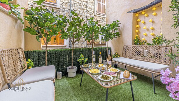 A cozy outdoor seating area with a table set for a meal, surrounded by potted plants and a stone wall. - Renovated House: Peace & Comfort 20 min from Monaco (Peille)