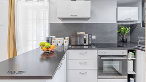 A modern kitchen with a built-in oven, a toaster, and a fruit bowl on the counter. - Renovated House: Peace & Comfort 20 min from Monaco (Peille)