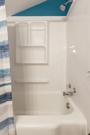 Une salle de bain avec une baignoire blanche, une douche et un porte-serviettes.