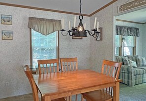 Enjoy meals in this stylish dining area with a wooden table, comfortable chairs, and a chandelier.