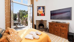 Ein Schlafzimmer mit Bett, Kamin, Fernseher und Blick ins Freie.