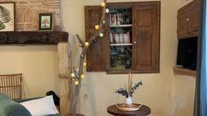 A cozy living room with a green sofa, a wooden bookshelf, and a decorative branch with lights.