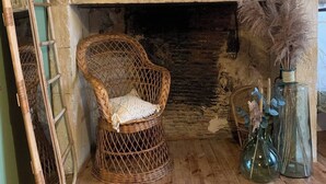 A rustic room with a stone fireplace, a wicker chair, a ladder, and decorative vases.