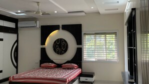 Een moderne slaapkamer met een bed, een plafondventilator, inbouwverlichting en een raam met zonwering.
