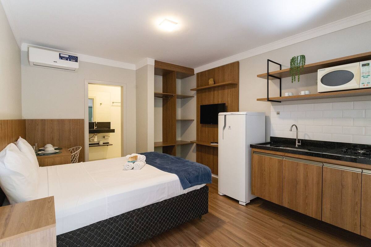 Een compacte hotelkamer met een bed, een klein kitchenette, een koelkast en een magnetron.