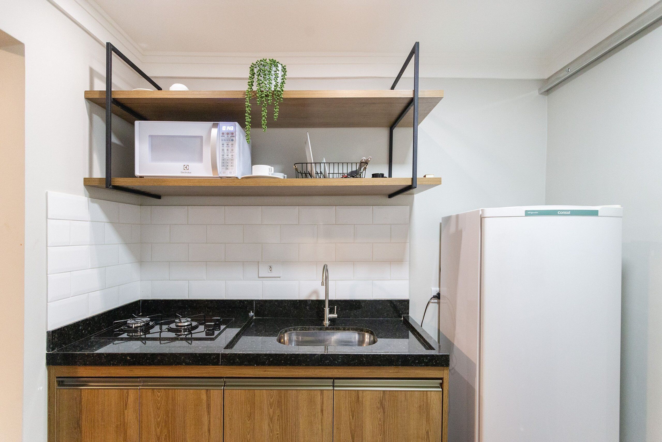 A kitchen with a black countertop, stainless steel sink, and a white refrigerator.