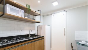 Une cuisine moderne équipée d’un four à micro-ondes, d’une cuisinière et d’un réfrigérateur encastrés. On y trouve également un meuble en bois et un évier avec un robinet.