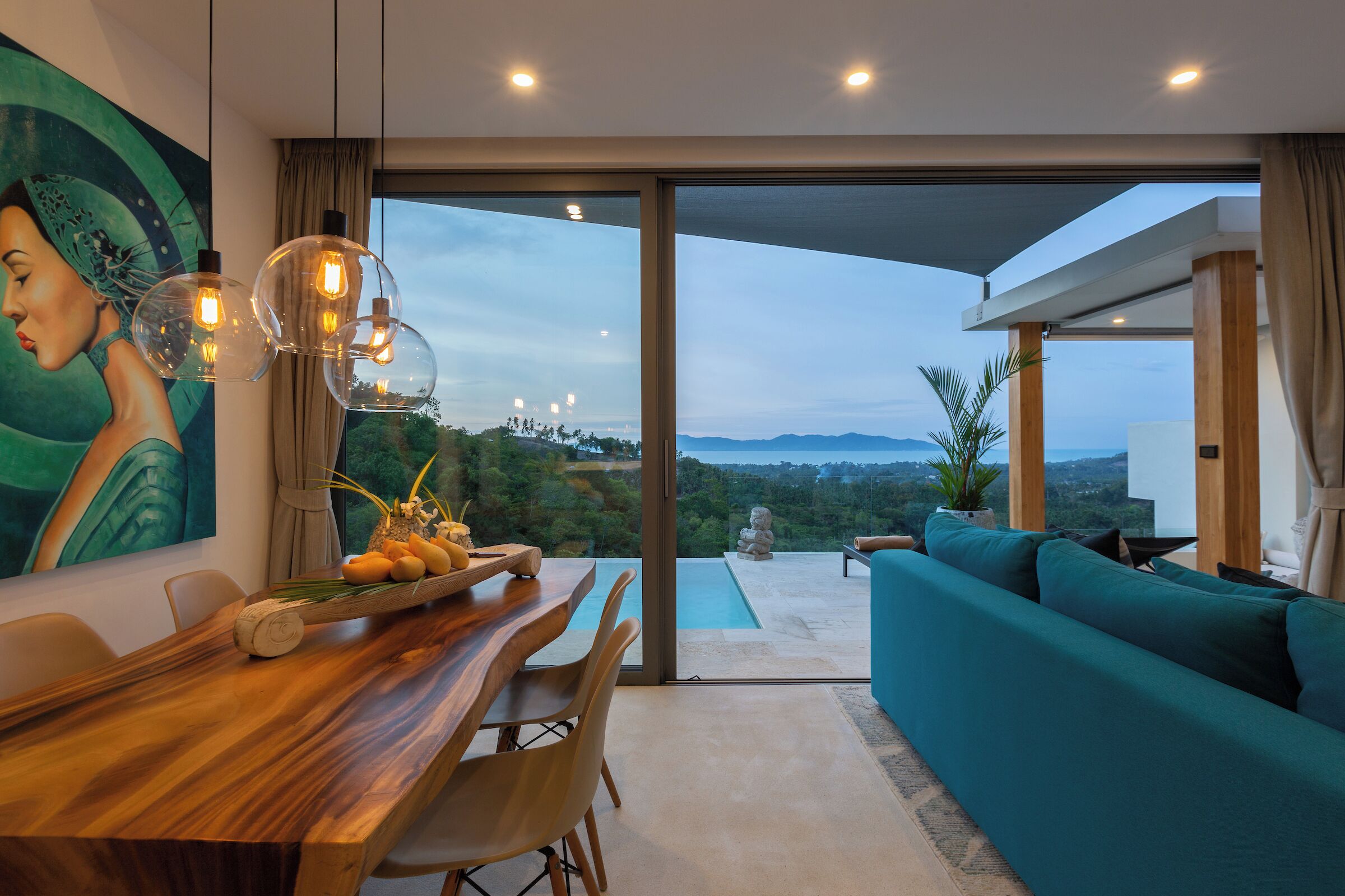 Un comedor moderno con una mesa de madera, sillas y vistas al exterior a través de amplios ventanales.