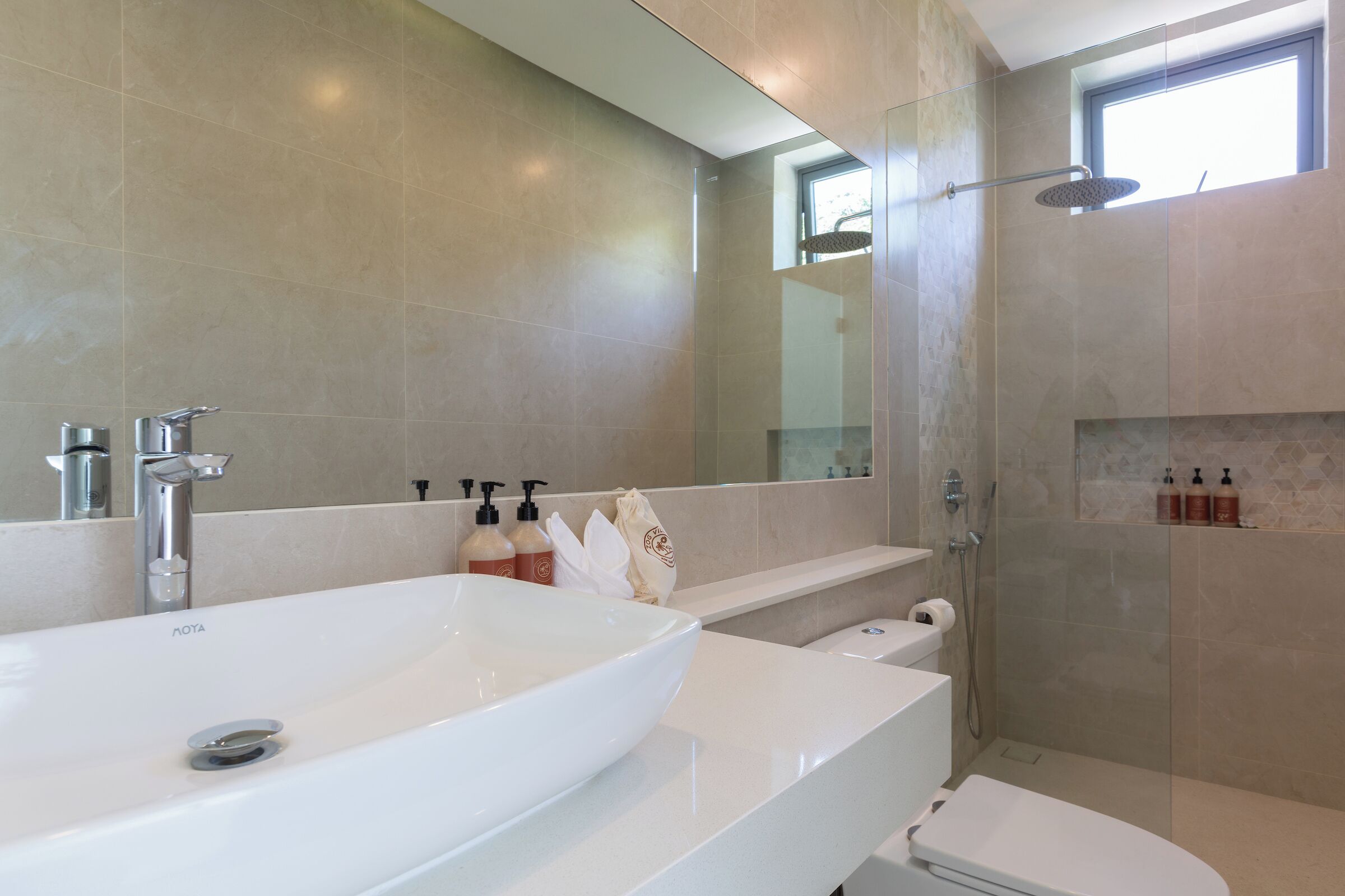 A modern bathroom with a large white sink, a glass-enclosed shower, and a mirror above the sink.