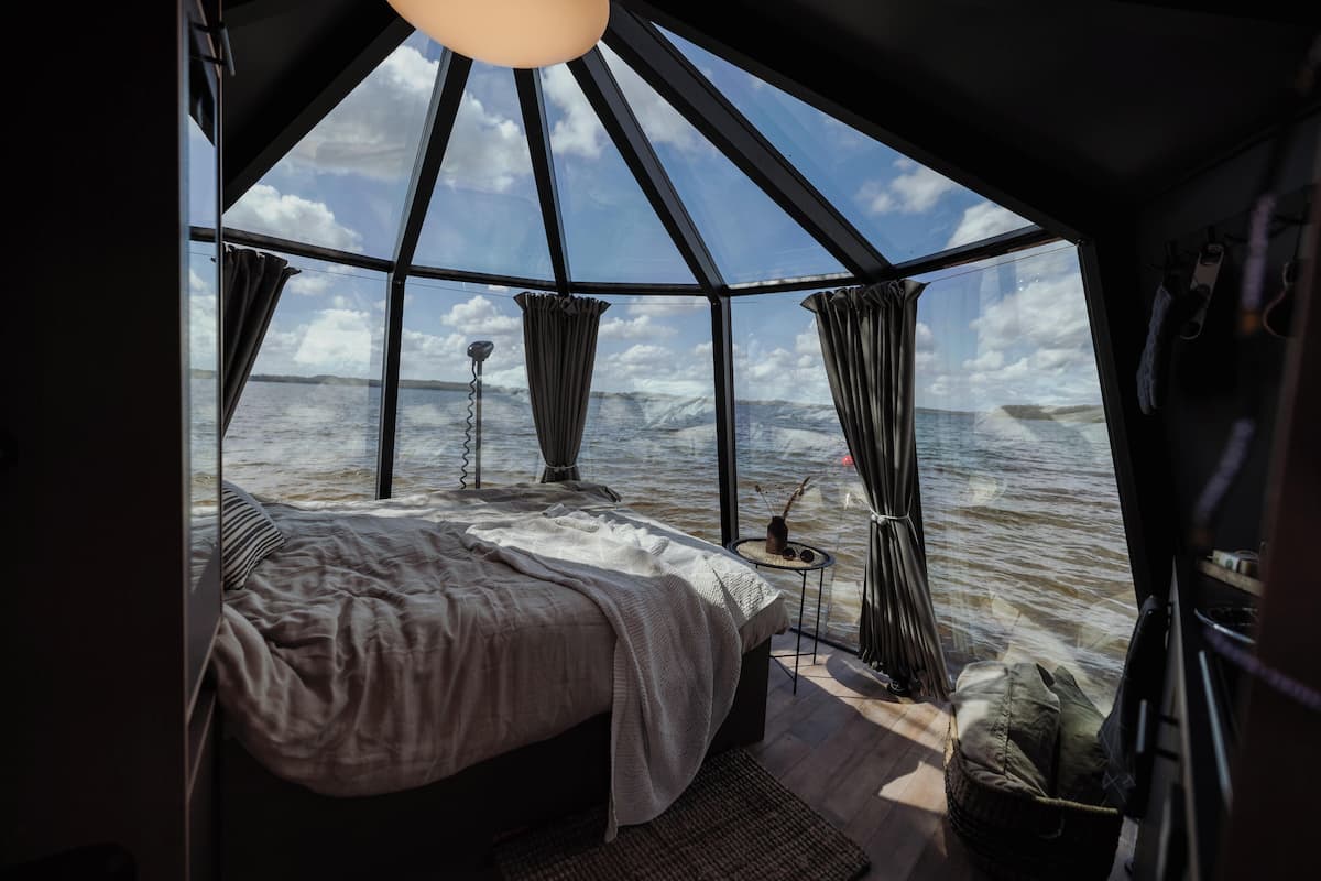 Een gezellige, moderne kamer met een groot bed, een klein tafeltje en uitzicht op de oceaan.