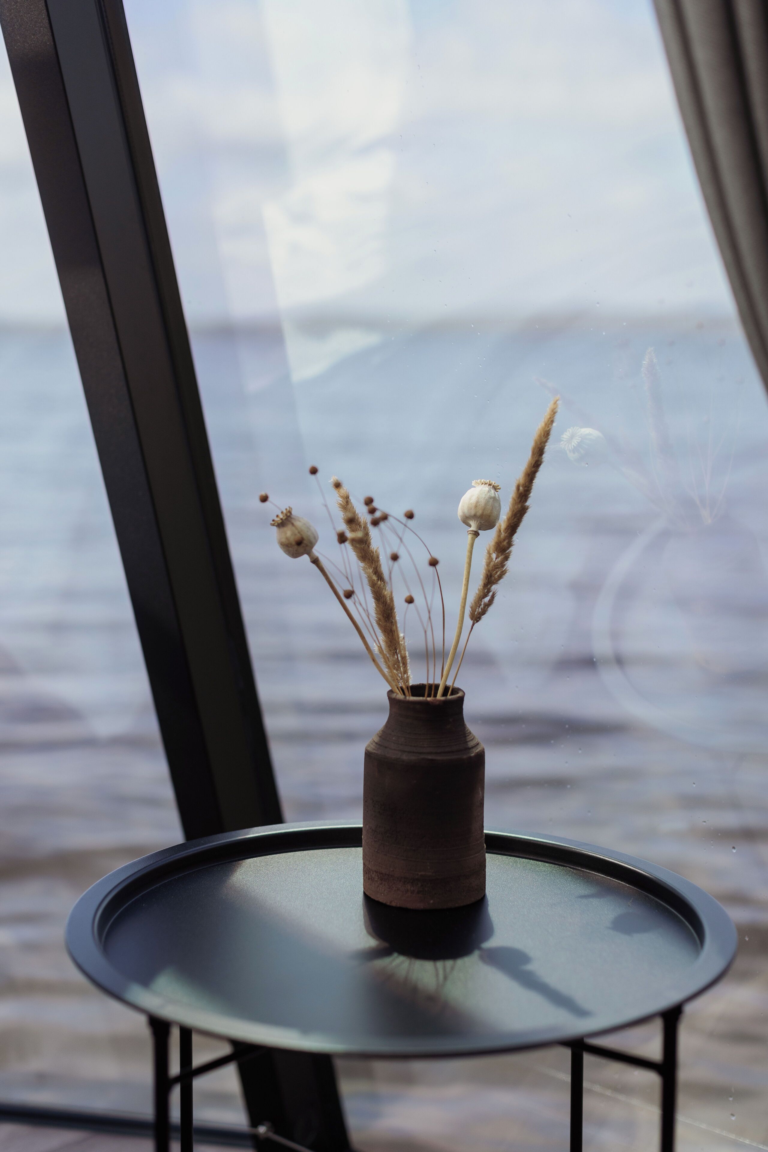 A small table with a vase of dried flowers.