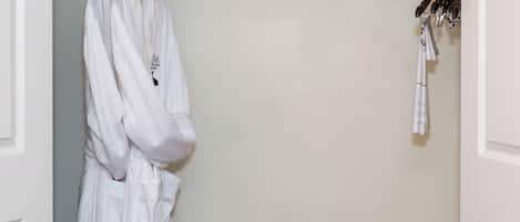 A white robe hanging on a hook, a wooden bench, and a wall-mounted device.