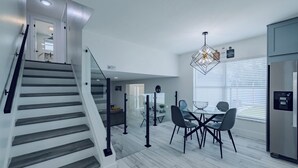 Una cocina moderna con comedor, escalera y refrigerador empotrado.