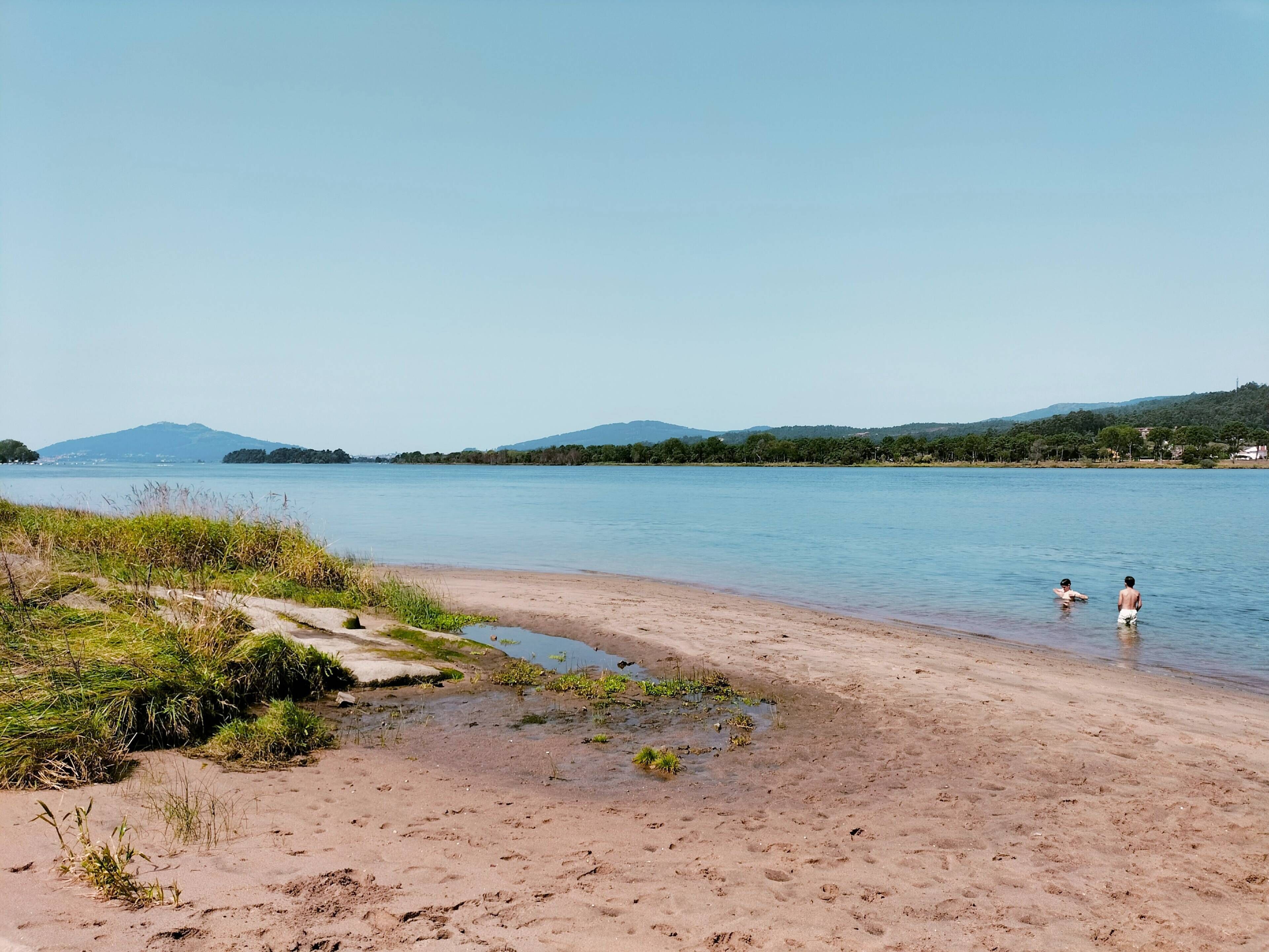 A beach with a clear view of the water and distant hills.