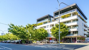 A modern multi-story building with balconies, a covered entrance, and a parking area with cars. - Elegant & Cosy Haven in Lively Kingston Foreshore (Kingston)