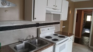 A kitchen with white cabinets, a double sink, and a stove.