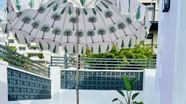 A rooftop terrace with a pool, striped outdoor furniture, and a decorative umbrella. - Petit Pineapple House Villa & Guesthouse (Cape Town)