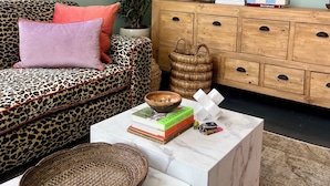 A living room with a sofa, a coffee table, a cabinet, and wall decorations including a lamp and framed pictures. - Petit Pineapple House Villa & Guesthouse (Cape Town)