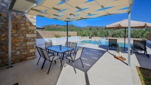 A patio with a pool, outdoor seating, and a stone wall.