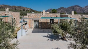 A stone building with a green roof, a staircase, and a view of mountains.