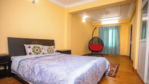 A bedroom with a bed, a nightstand, a hanging chair, and a window with curtains.