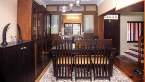 A dining area with a wooden table and chairs, a cabinet, and hanging lights.