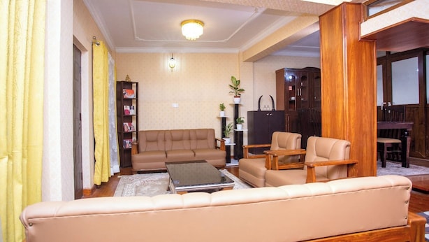A living room with a sofa, two armchairs, a coffee table, a bookshelf, and a cabinet.