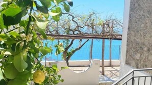 A balcony with a view of the sea, a stone wall, and a metal railing. - Villa Pino (Furore)