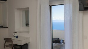 A room with a desk, chair, and a view of the sea through a door. - Villa Pino (Furore)