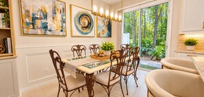 A dining area with a glass-top table, ornate chairs, and artwork on the walls. - Extended-Stay Home  30, 60, 90+ Days  W/ Secure Work Trailer Parking Available (Jacksonville)