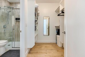Ein modernes Badezimmer mit einer Duschkabine aus Glas, Toilette, Waschbecken und Spiegel.