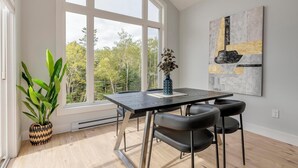 Un comedor moderno con un ventanal grande, una mesa, sillas y una planta en maceta.