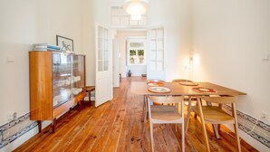 Un área de comedor con una mesa y sillas de madera, un mueble con puertas de vidrio y una lámpara colgante.