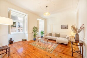 A living room with hardwood flooring, a sofa, a coffee table, and potted plants. - GuestReady - A perfect home in the heart of Lisbon (Lisbon)