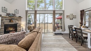 Ein geräumiges Wohnzimmer mit Kamin, großen Fenstern und Meerblick.