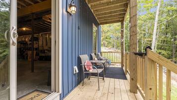 Un patio in legno con posti a sedere all'aperto, una parete esterna blu e un tappetino d'ingresso.
