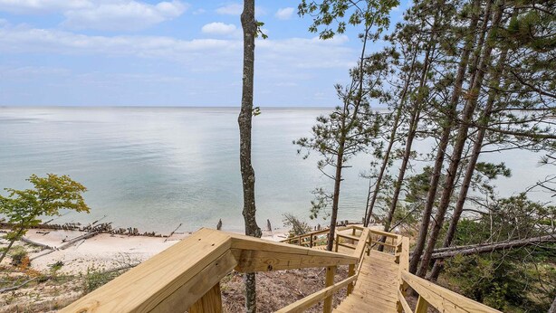 Eine Holztreppe führt zu einem Strand mit Blick auf das Meer.
