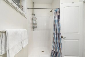 Ein Badezimmer mit Dusche, Handtuchhalter und einer Tür.