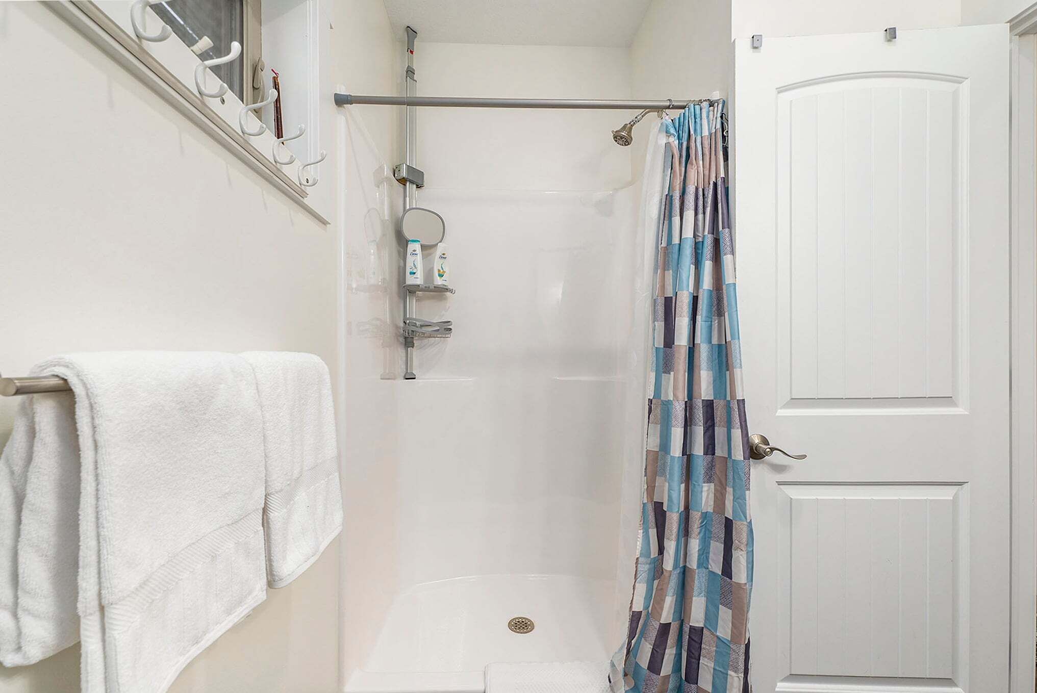 A shower with a towel rack, a shower curtain, and a door.