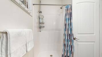 A shower with a towel rack, a shower curtain, and a door.