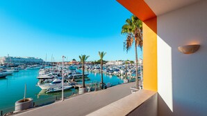 A marina with boats docked, palm trees, and a clear blue sky. - Apartment Portobello (Loulé)