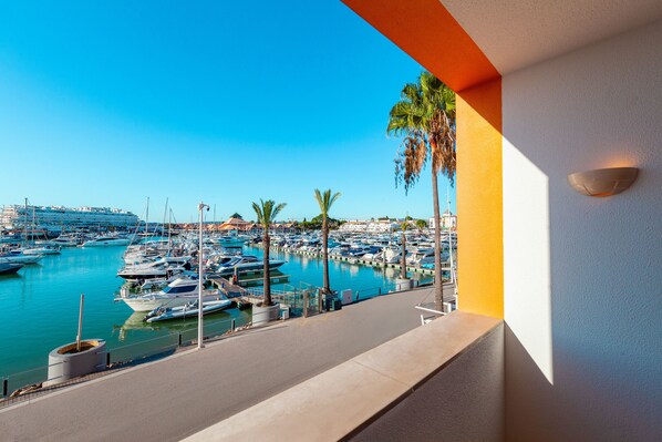 A marina with boats docked, palm trees, and a clear blue sky.