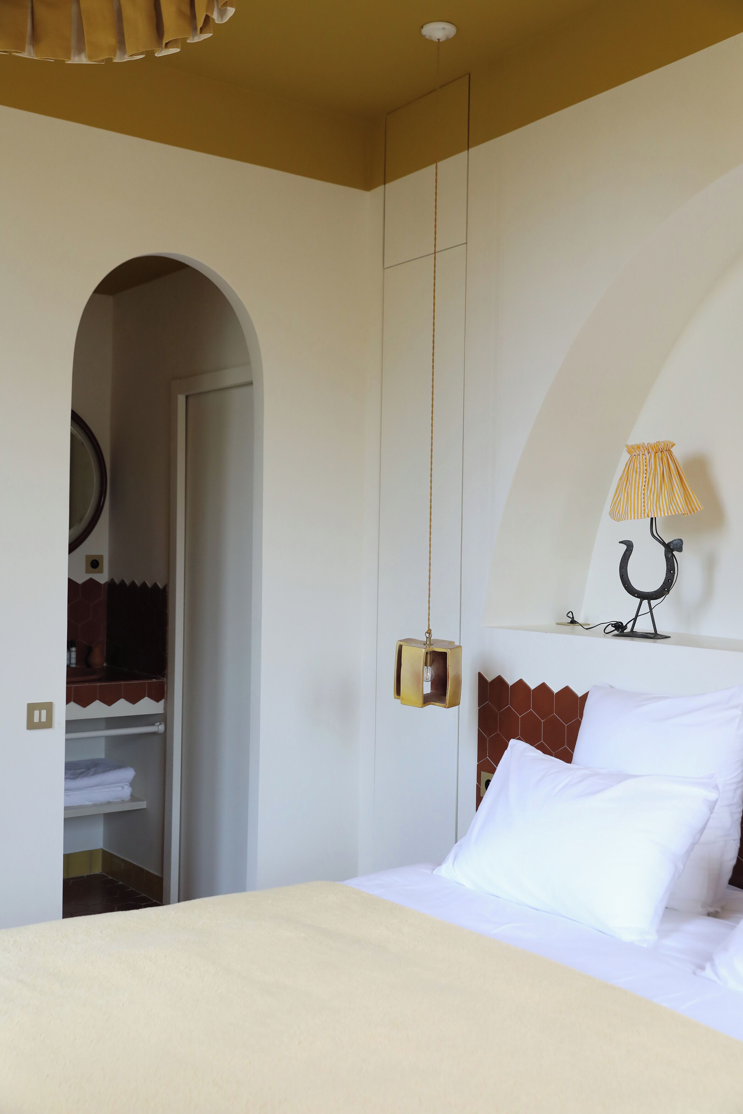 A bedroom with a bed, a hanging lamp, and a wardrobe.